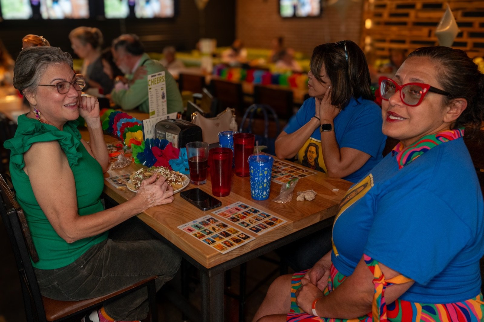 Players at a table with lotería tablas laid out