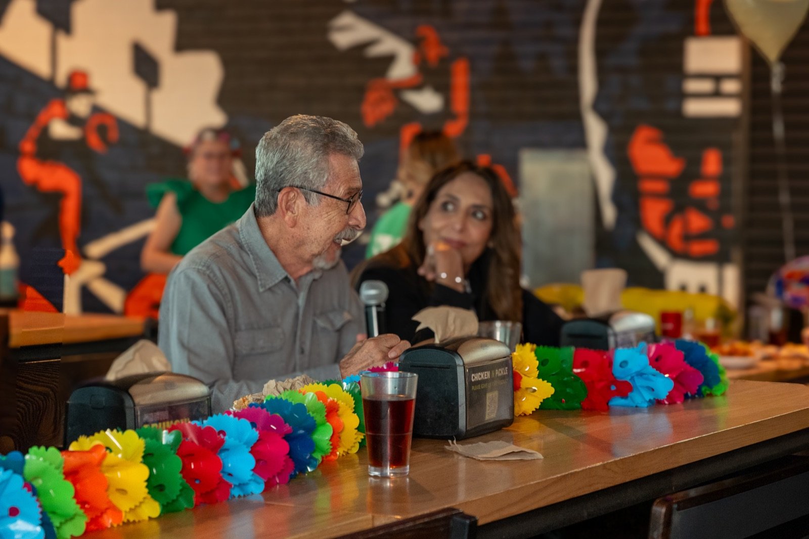The lotería caller announcing cards on the microphone