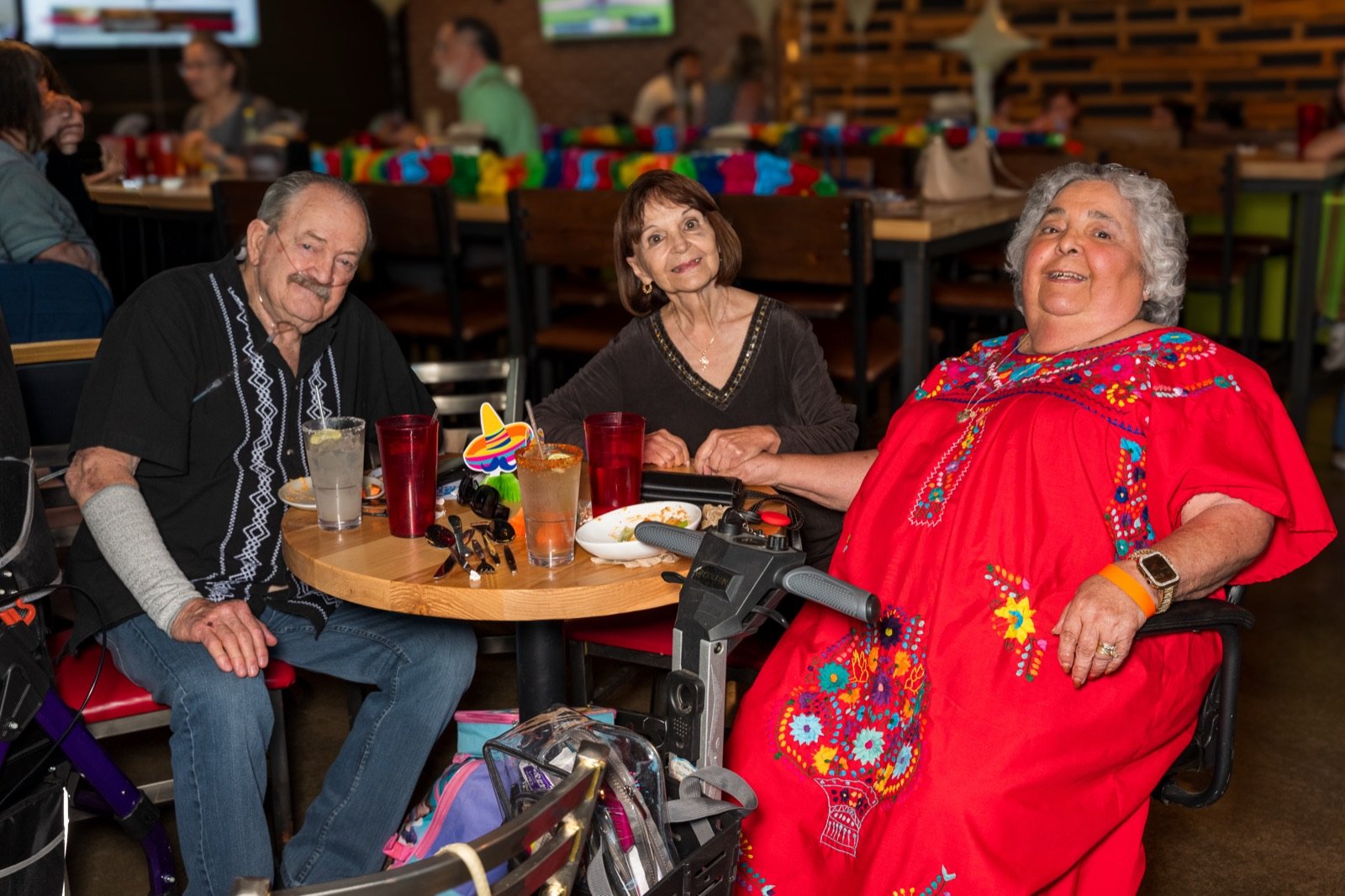 Three guests in festive dress smiling at their table