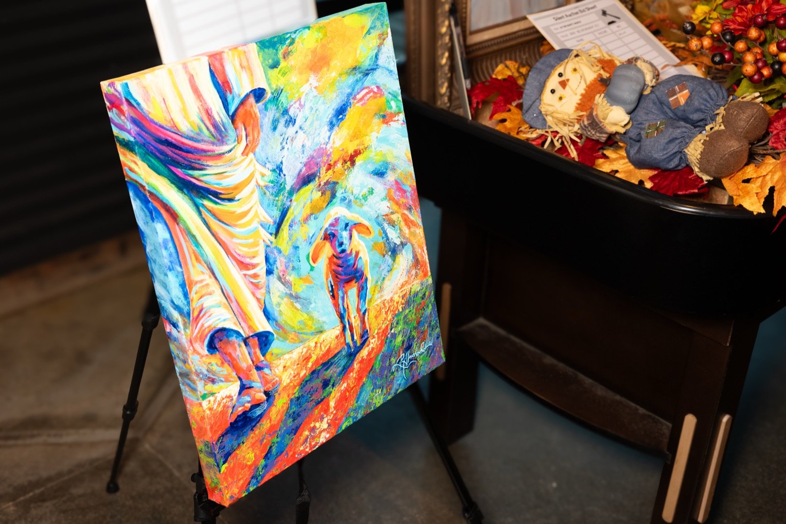 A colorful painting on an easel in the silent auction